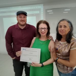 Professores posam para a foto com certificado em mãos, após docente ministrar palestra